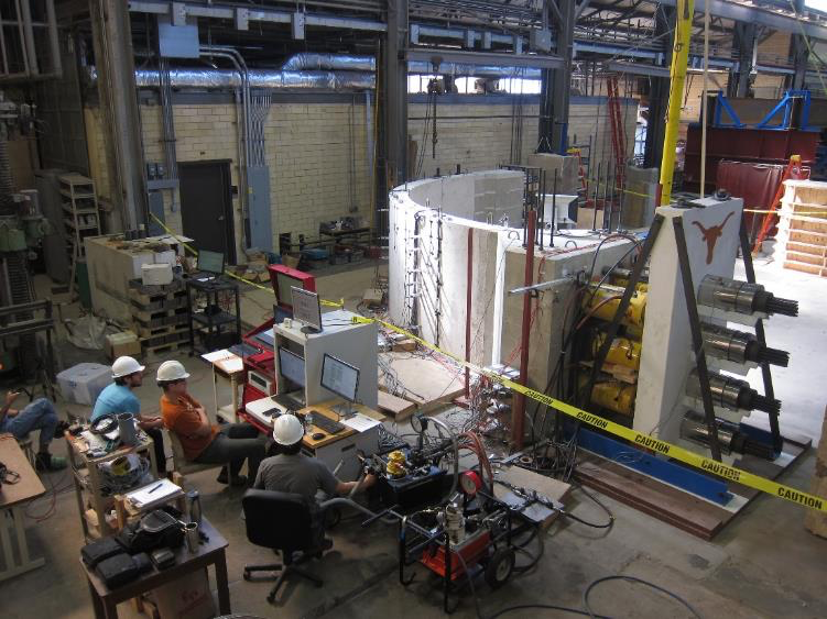 3 men looking at computers while concrete testing happens inside warehouse