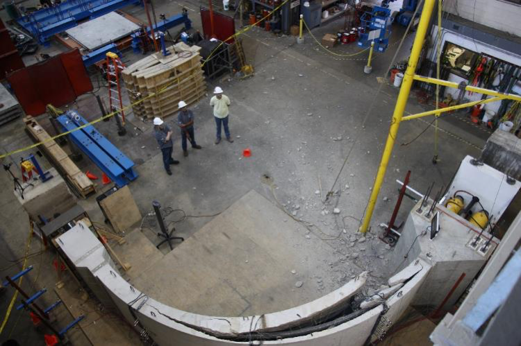 3 men looking at cracked curved concrete structure