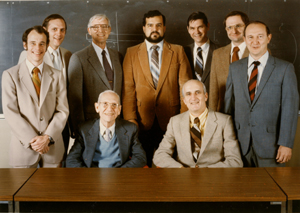 group of men in suits standing behind a desk
